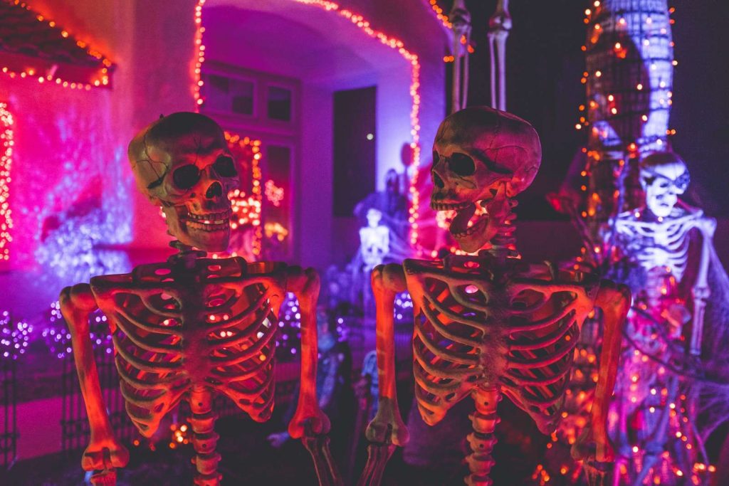 pair of skeletons in front of Halloween house
