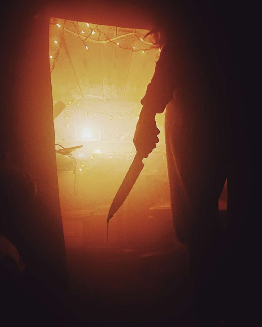 scary killer holding knife in doorway