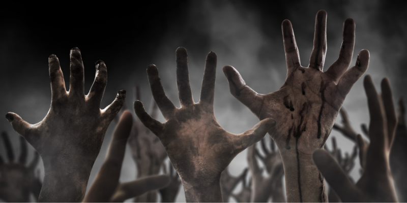 zombie hands coming out of the ground in a graveyard