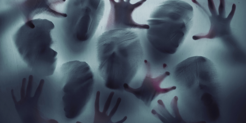 faces and hands pressing up against a translucent piece of fabric trying to get through