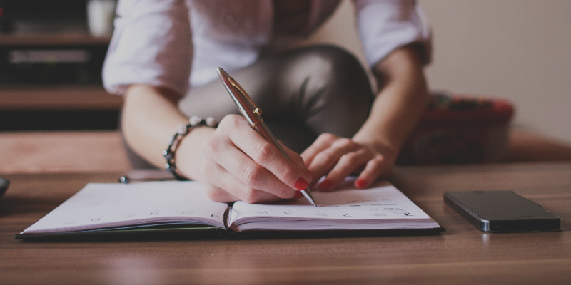 Image of a person writing in a planner