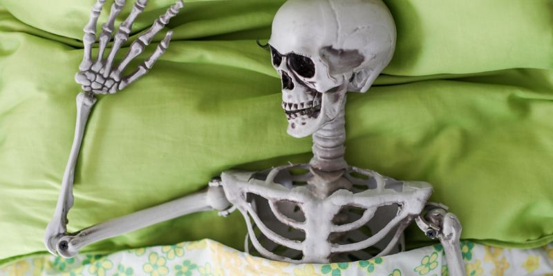 Skeleton laying in bed sleeping