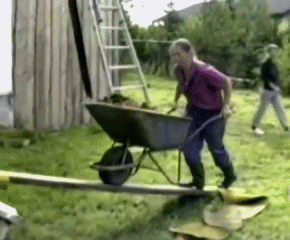 Man pushing a wheelbarrow of dirt trips and dumps the dirt on himself