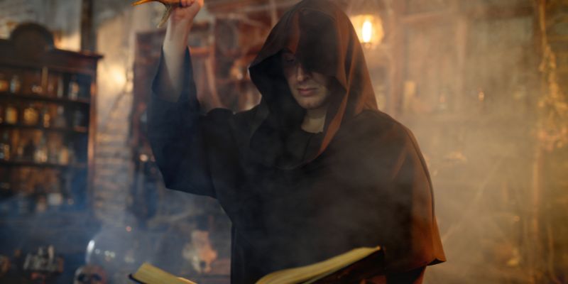 man in a robe holding a book and antlers