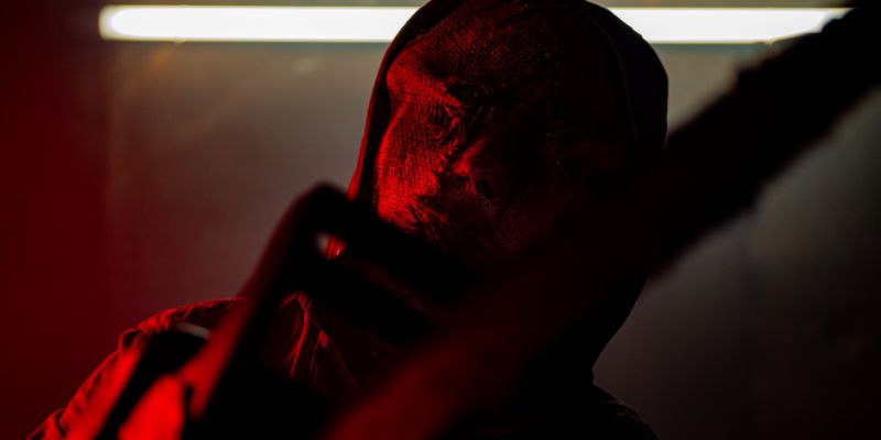 scary man with burlap covering face under red light