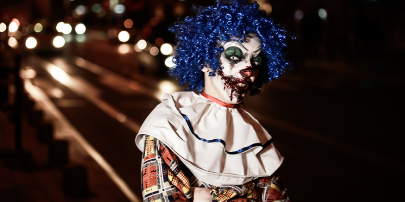 Scary horror clown standing in a road.