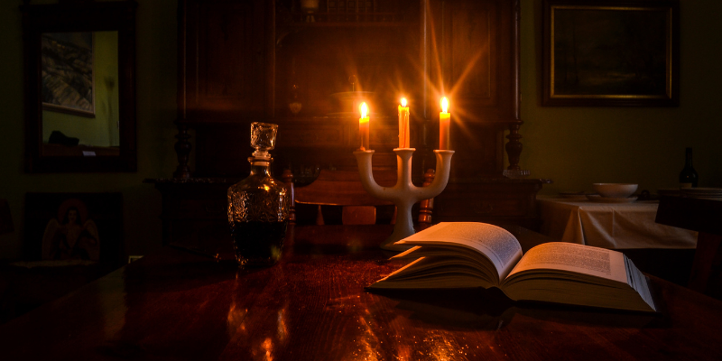 Candlelit room with a book open on a table.