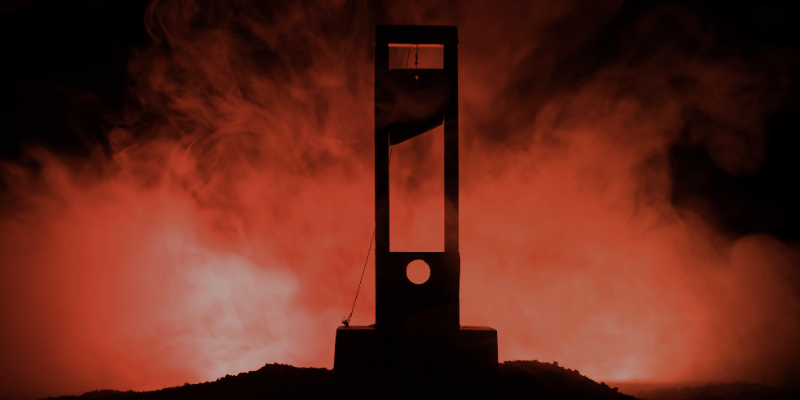 Guillotine silhouette in smokey orange shadows