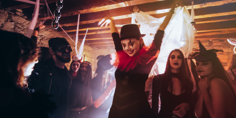 Woman and friends in scary costumes and makeup having fun at Halloween party