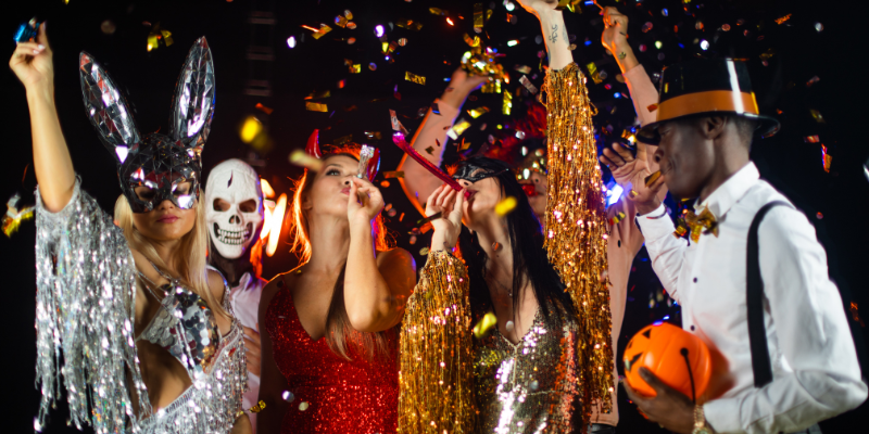 Happy men and women mixed race dancing together at a Halloween party in glittery costumes