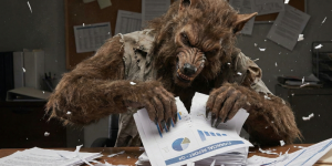 Werewolf sitting at an office desk tearing apart a stack of financial reports