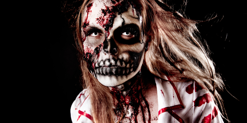 Woman with long hair in skeleton zombie makeup against a black background