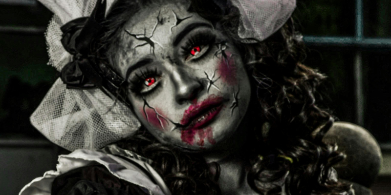 Women in creepy doll costume and makeup with glowing red eyes
