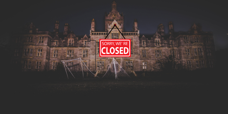 Exterior view of an old haunted castle with a "sorry we're closed" sign pinned to the front of the building