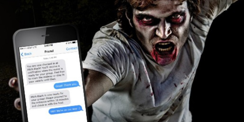 Zombie guy lurching toward the camera holding a Mobile phone displaying the HauntPay virtual queue SMS messages