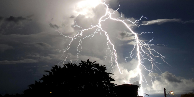 Dramatic lightning storm against a beautiful sky above house and trees