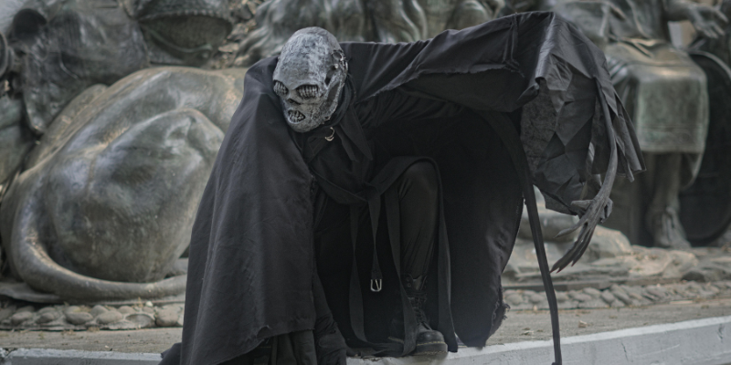 Mysterious figure in a dark cloak with a skull head with teeth for eyes