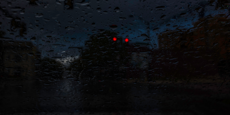 Raindrops through the windshield with red dots or eyes glowing through the window