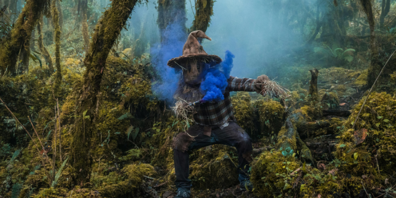 Scarecrow monster with blue smoke flare in a mossy forest